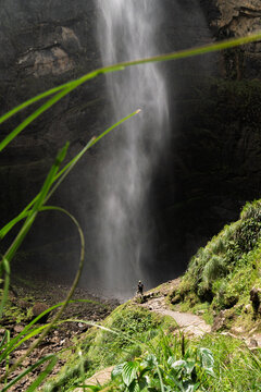 Hiker standing at base of Gocta Falls, highlighting dramatic scale, Peru