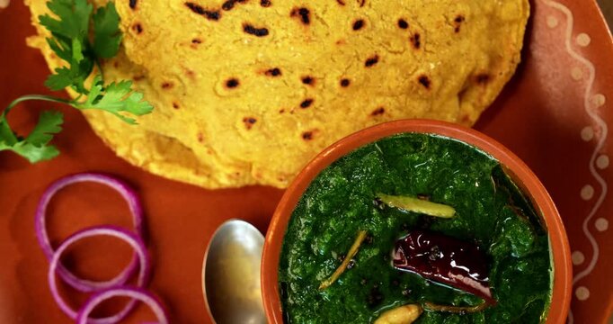 Makki Ki Roti & Sarson Ka Sag is basically Corn floor flat bread & curry using mustard greens respectively. Popular Punjabi food. Served in a bowl and plate over moody background. selective focus