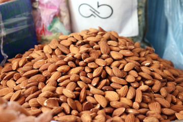 Almonds close up showing large mound of raw unblanched nuts in bright market setting