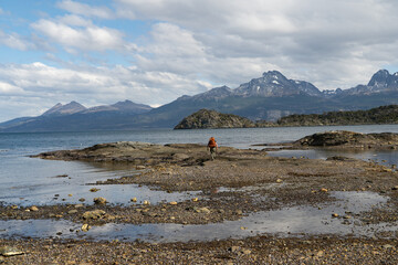 Hiker walking across rocky tidal flats of Beagle Channel, Tierra del Fuego