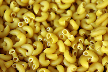 Elbow macaroni pasta uncooked golden yellow pasta background