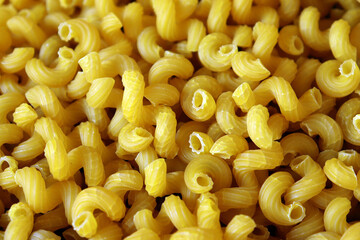 Elbow macaroni pasta uncooked golden yellow pasta background