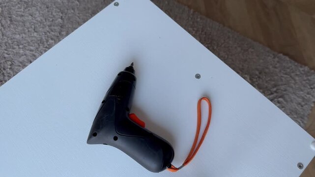 Cordless electric screwdriver on white furniture - with the tip facing to the right