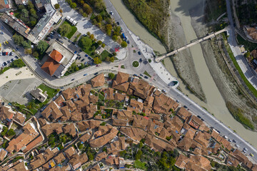 Top-down view of Berat showing its tiled-roof old town, riverside streets and pedestrian bridge crossing the Osum River.