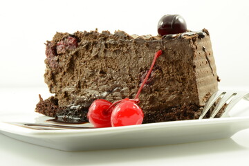 Słodki deser w postaci czekoladowego ciasta z polewą ozdobionego kandyzowanymi wiśniami  © piotr