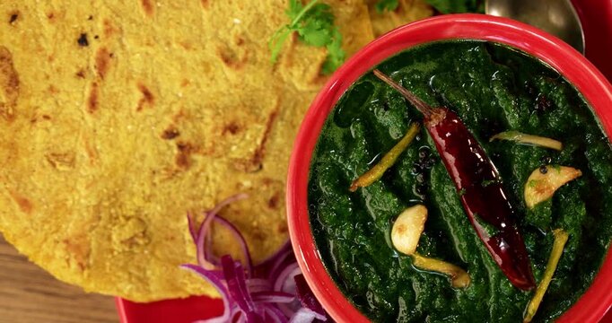Makki Ki Roti & Sarson Ka Sag is basically Corn floor flat bread & curry using mustard greens respectively. Popular Punjabi food. Served in a bowl and plate over moody background. selective focus