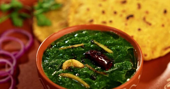 Makki Ki Roti & Sarson Ka Sag is basically Corn floor flat bread & curry using mustard greens respectively. Popular Punjabi food. Served in a bowl and plate over moody background. selective focus