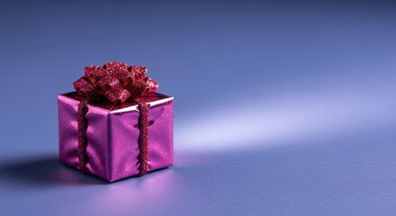 Small shiny pink gift box with glitter bow on blue