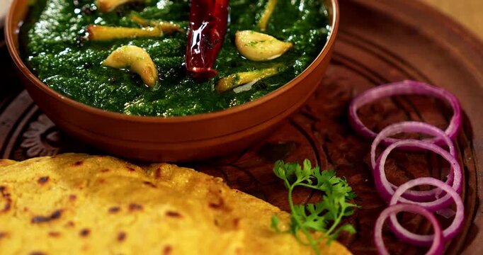 Makki Ki Roti & Sarson Ka Sag is basically Corn floor flat bread & curry using mustard greens respectively. Popular Punjabi food. Served in a bowl and plate over moody background. selective focus