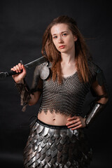 Obraz premium Portrait of a young woman, fantasy warrior in armor with a sword in her hands isolated on a dark background.