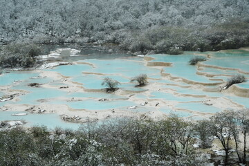 Panoramic View of Icy Blue Travertine Pools and Snow-Dusted Forest in Huanglong National Park.