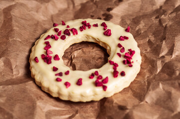 Delicious ring-shaped cookie with white icing and dried raspberry topping