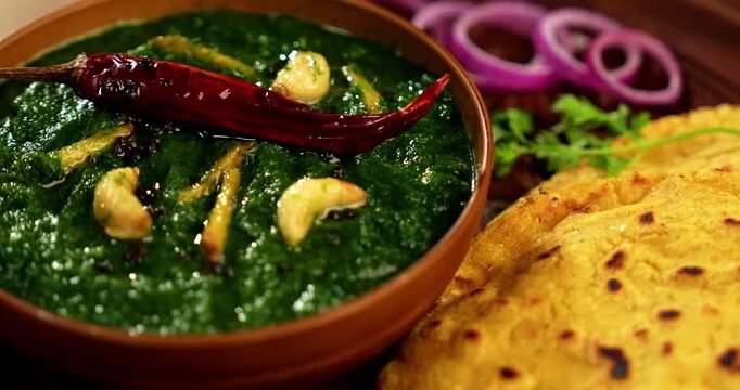 Makki Ki Roti & Sarson Ka Sag is basically Corn floor flat bread & curry using mustard greens respectively. Popular Punjabi food. Served in a bowl and plate over moody background. selective focus