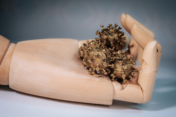 Close-up of a hand holding several small bronze sculptures in the shape of stylized viruses with...