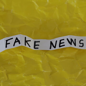 Una toma de cerca de un papel blanco con la palabra noticias falsa en un fondo amarillo