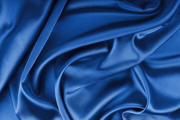 Crumpled, wrinkled blue colored glossy silk satin with wave drapery.. Shiny smooth fabric with soft folds, cloth texture . Elegant rich background, wallpaper, backdrop. Flat lay, top view