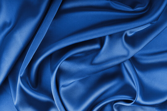 Crumpled, wrinkled blue colored glossy silk satin with wave drapery.. Shiny smooth fabric with soft folds, cloth texture . Elegant rich background, wallpaper, backdrop. Flat lay, top view - Powered by Adobe