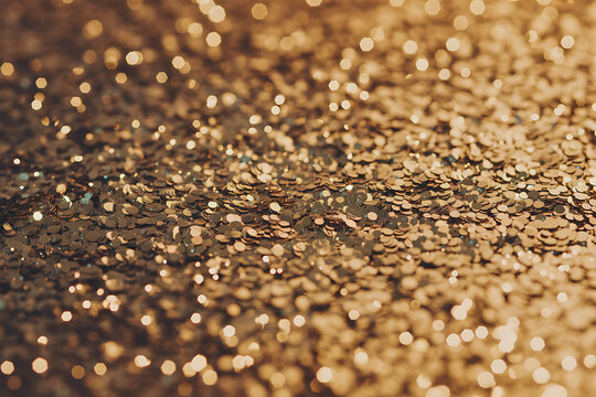 Closeup of shimmering golden glitter particles, creating a bokeh effect with soft focus