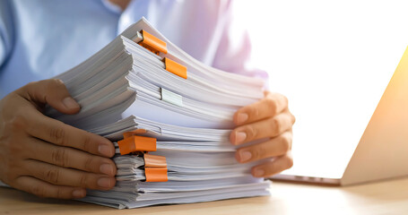 Person holding large stack of paper document with orange binder clip