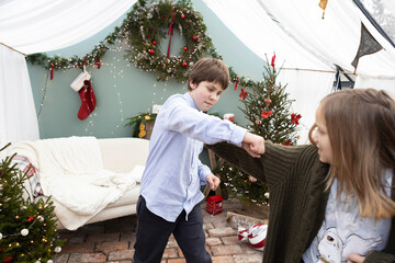 Children enjoying a playful moment in a festive winter setting decorated with holiday cheer