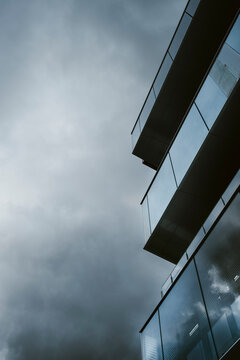 Architecture shaping the skyline through an urban layout featuring building facade and glass reflection across the modern city surrounded by a dramatic sky granting clear copy space