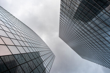 Architecture shaping a skyline in an urban view featuring building facade and vivid glass reflection across the modern city under a dramatic sky providing spacious copy space