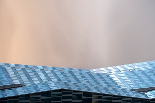 Architecture leading the skyline through an urban composition where building facade and glass reflection highlight the modern city beneath a dramatic sky offering clear copy space