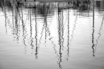 maszty żaglowców odbite w wodzie, czarno-biały obraz masztów odbitych w wodzie, sailboat masts reflected in the sea water  © kateej