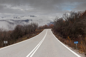 Rural road in the mountains in winter (Epirus region, Greece) on a cloudy, foggy day