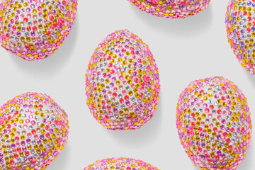 Repeat design of pink shiny eggs with vibrant stones on grey background, creative flat lay of sparkly Chicken egg, minimal pastel pattern, for packaging, social media, Easter food celebration concept.