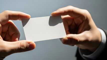 Holding a blank white business card between two hands, ready for contact information