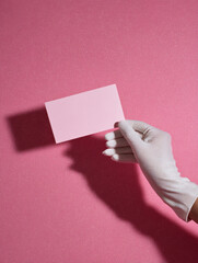 Glam hand in white glove holding blank pink card for stylish promotional branding