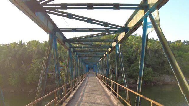Going through Sadolxem bridge surrounded by tropical greenery at golden sunset in South Goa, India