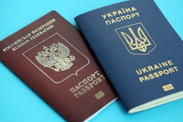 Ukraine and Russian Federation passports on light blue table background close up. Concept of...