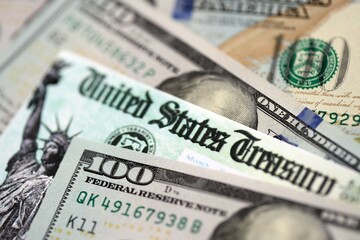 United States Treasury refund check or stimulus bill with many hundred dollars banknotes close up