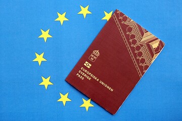 Swedish biometrical passport on European Union flag background. Concept of citizenship of Sweden