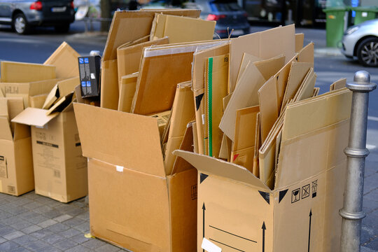 broken cardboard boxes with waste paper, next to paper recycling bin recycling problem, urban waste management, raw material for recycling, environmental contamination and neglect