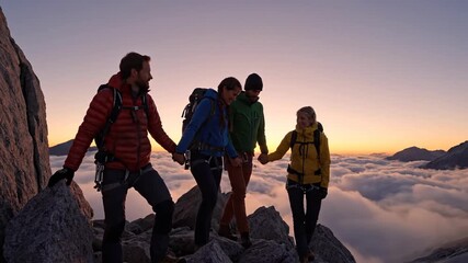 Group of hikers climbing rocky mountain ridge above clouds at sunset - Powered by Adobe