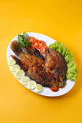 Food photography showcasing Indonesian-style grilled gourami fish served with sambal and vegetables