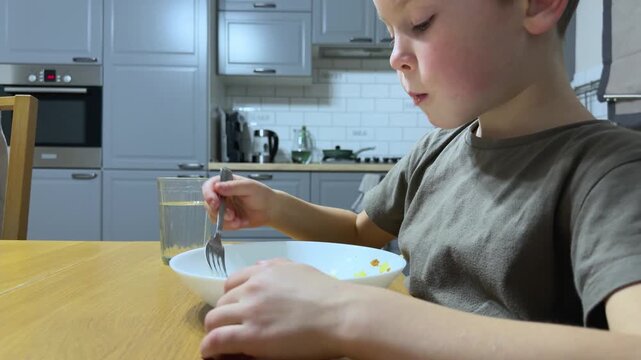 side angle close view of child eating pasta alone using fork focusing on coordination and independence natural kitchen environment childhood growth Concept of self sufficiency and developing daily