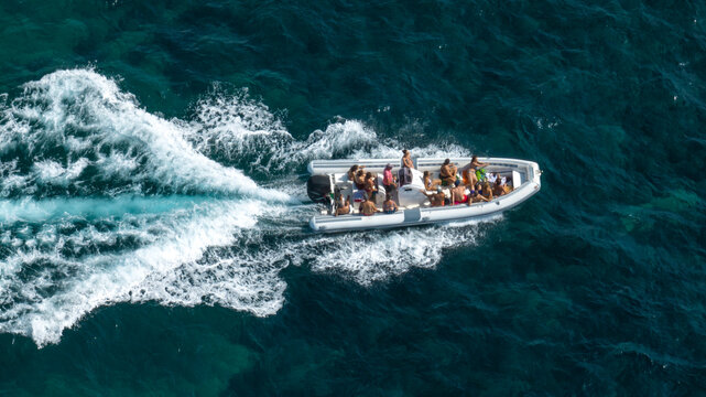 Aerial view of people on vacation on a dinghy sailing the blue sea. Holiday boat concept.