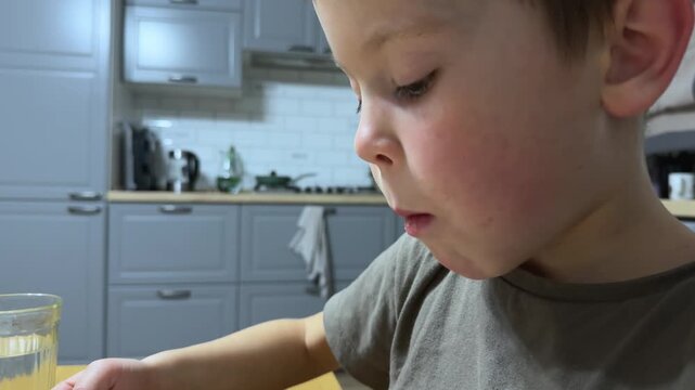 side view of 7 year old child eating pasta with fork from white plate kitchen setting real life meal moment natural behavior family home atmosphere Concept of everyday childhood routine and simple