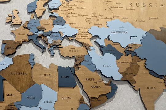 Detailed close-up of a wooden world map, showing countries in Europe, Middle East, and Asia with engraved city and country names.