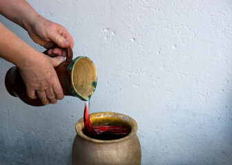 A hand holds a clay jar and pours water