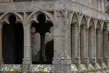 Historic cloister columns at Mont Saint-Michel showcasing medieval Gothic architecture. Gothic stone arches of Mont Saint-Michel Abbey with weathered textures and lichen details.