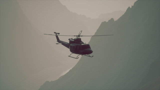 A helicopter soars gracefully above mist covered mountain slopes, capturing the serene beauty of the early morning light illuminating the rugged landscape. - Powered by Adobe
