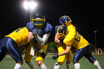American football players engaging in a tackle during a night game on a stadium field