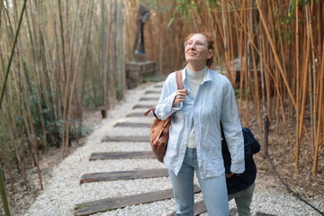 Woman smiling, looking up while walking in bamboo garden