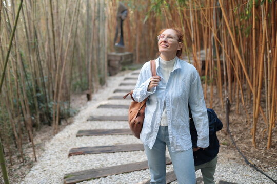 Woman smiling, looking up while walking in bamboo garden