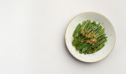 Stir-fry green beans with sesame and garlic on plate, top view, copy space